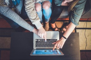 Three people working together on a laptop.